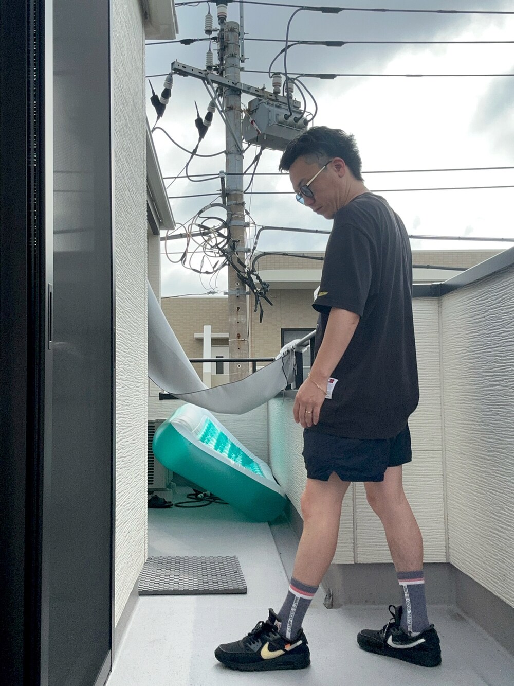 ブラック系のTシャツ/カットソー、ブルー系のパンツ、ブラック系のスニーカーを着用したメンズの夏コーディネートの3枚目の写真