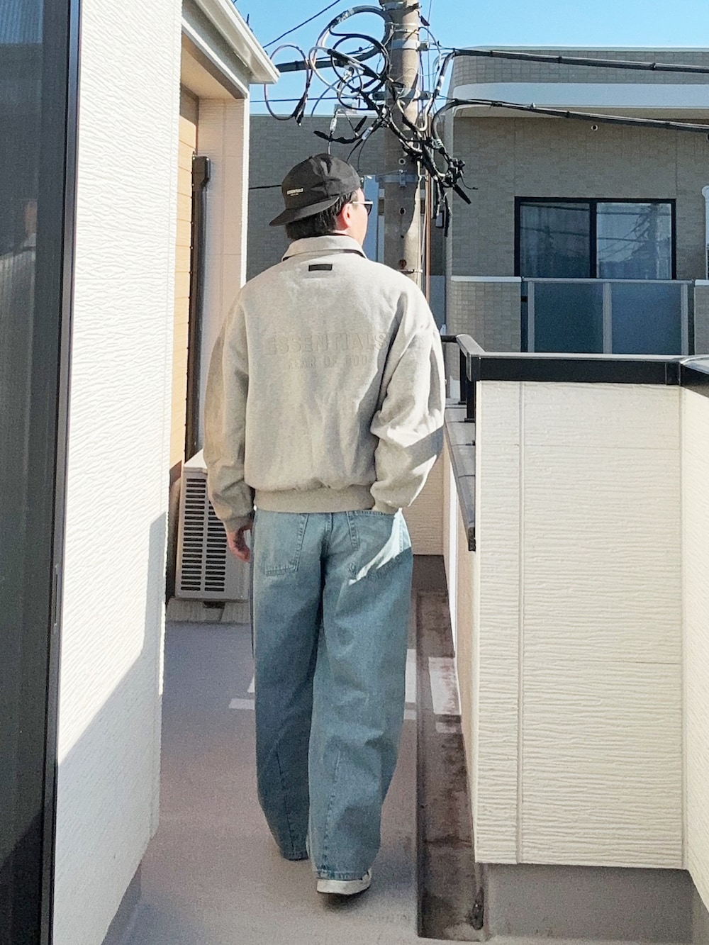 グレー系のポロシャツ、ブラック系のニット/セーター、ブルー系のデニムパンツを着用したメンズの冬コーディネートの2枚目の写真