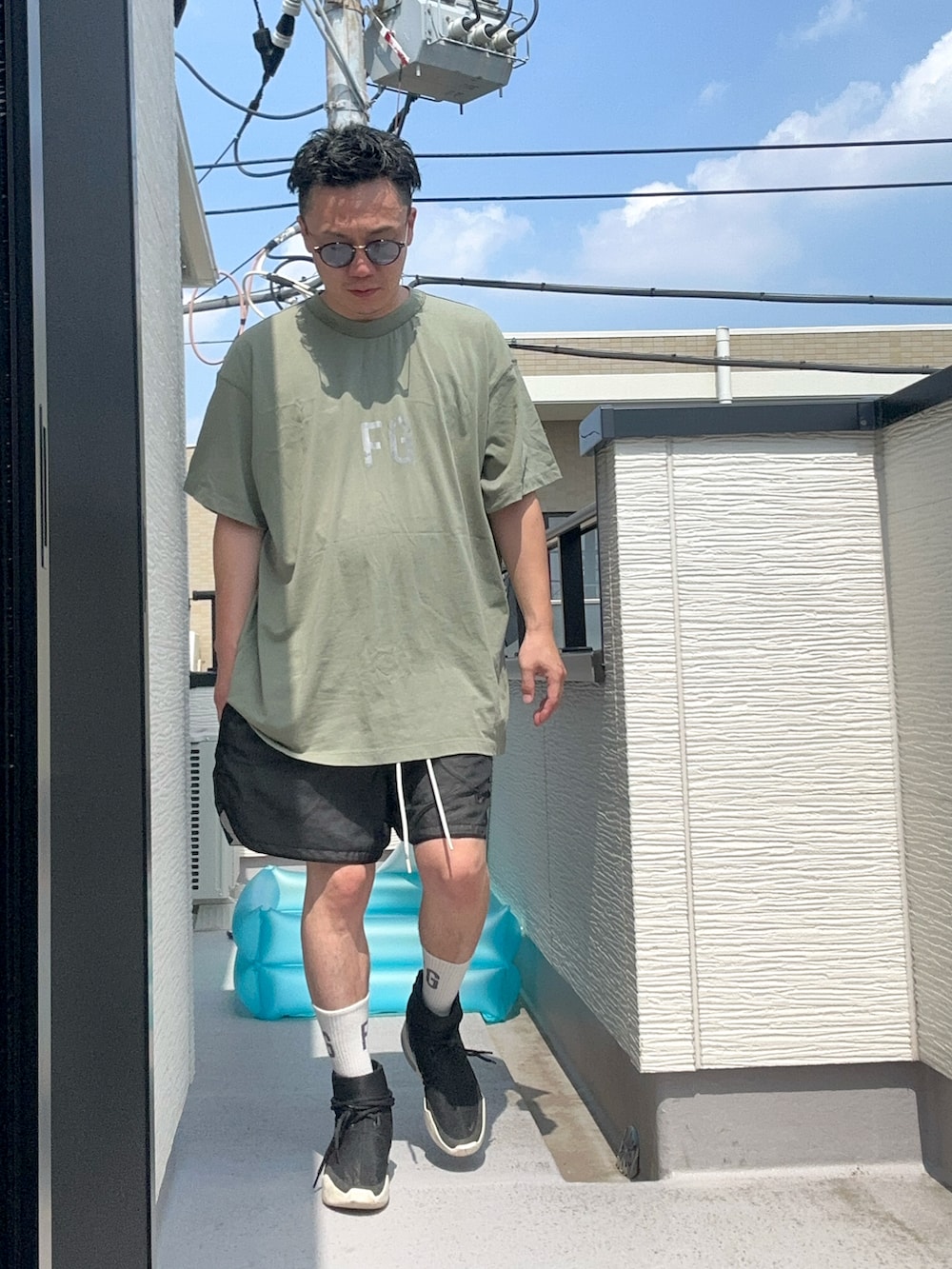 グリーン系のTシャツ/カットソー、ブラック系のパンツ、ブラック系のスニーカーを着用したメンズの夏コーディネートの2枚目の写真