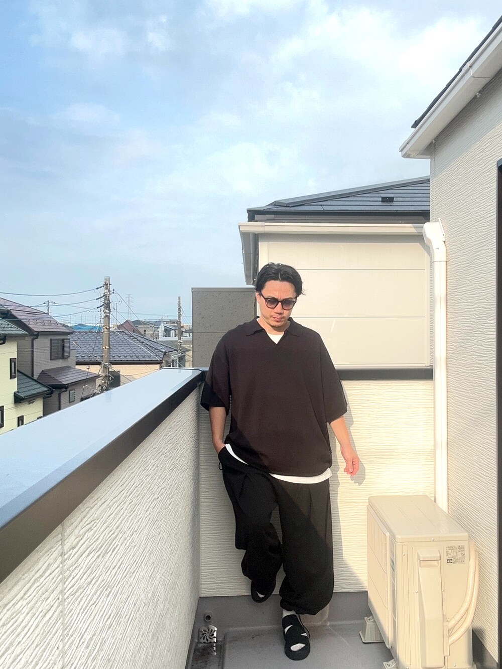 ブラック系のポロシャツ、ブラック系のスウェットパンツ、ブラック系のサンダルを着用したメンズの夏コーディネートの4枚目の写真