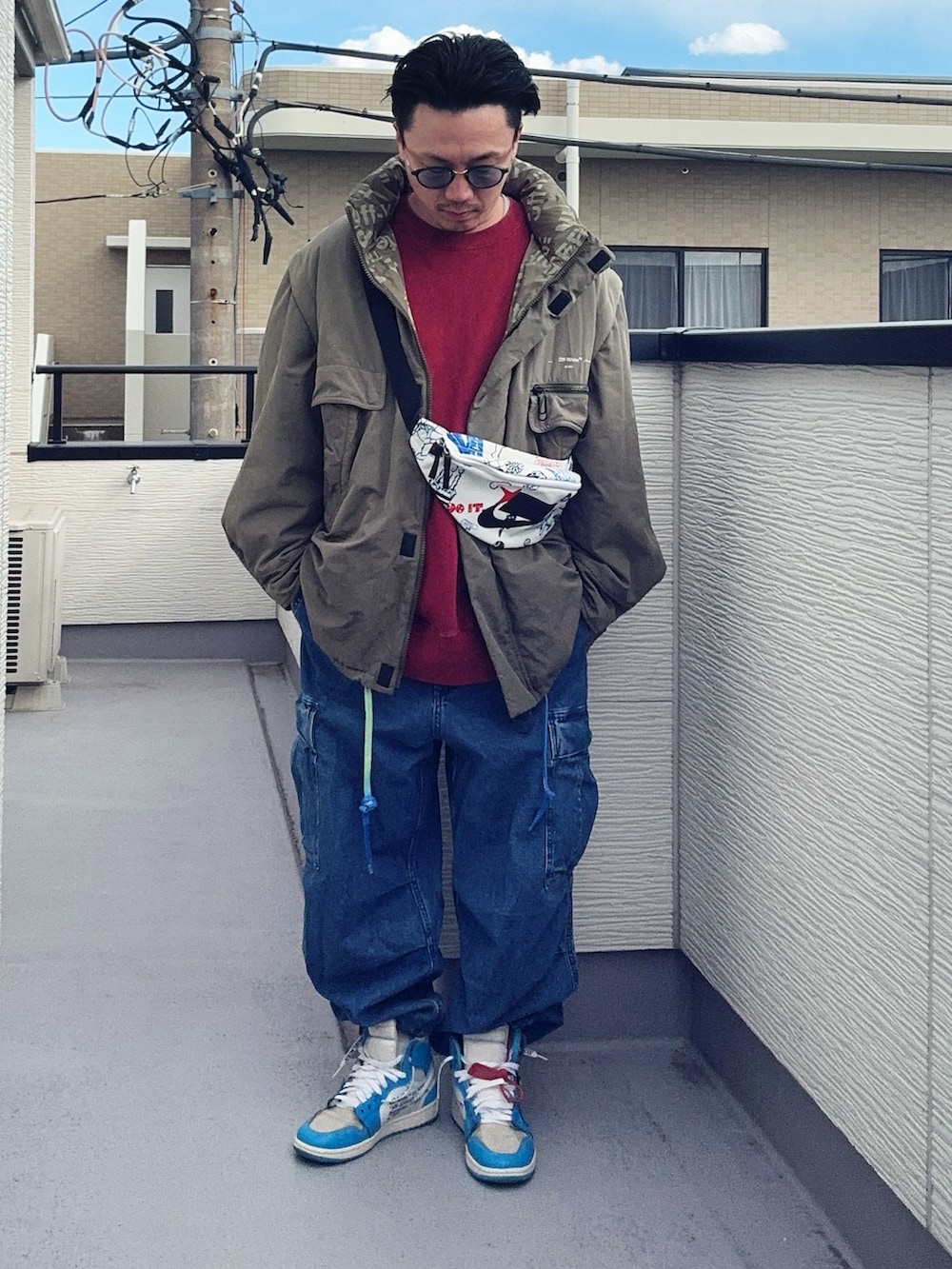 レッド系のスウェット、グリーン系のミリタリージャケット、ブルー系のカーゴパンツを着用したメンズの冬コーディネートの2枚目の写真