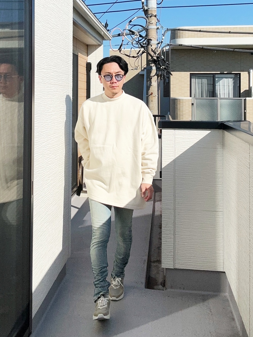 ベージュ系のスウェット、グレー系のスニーカー、ブルー系のデニムパンツを着用したメンズの秋コーディネートの2枚目の写真