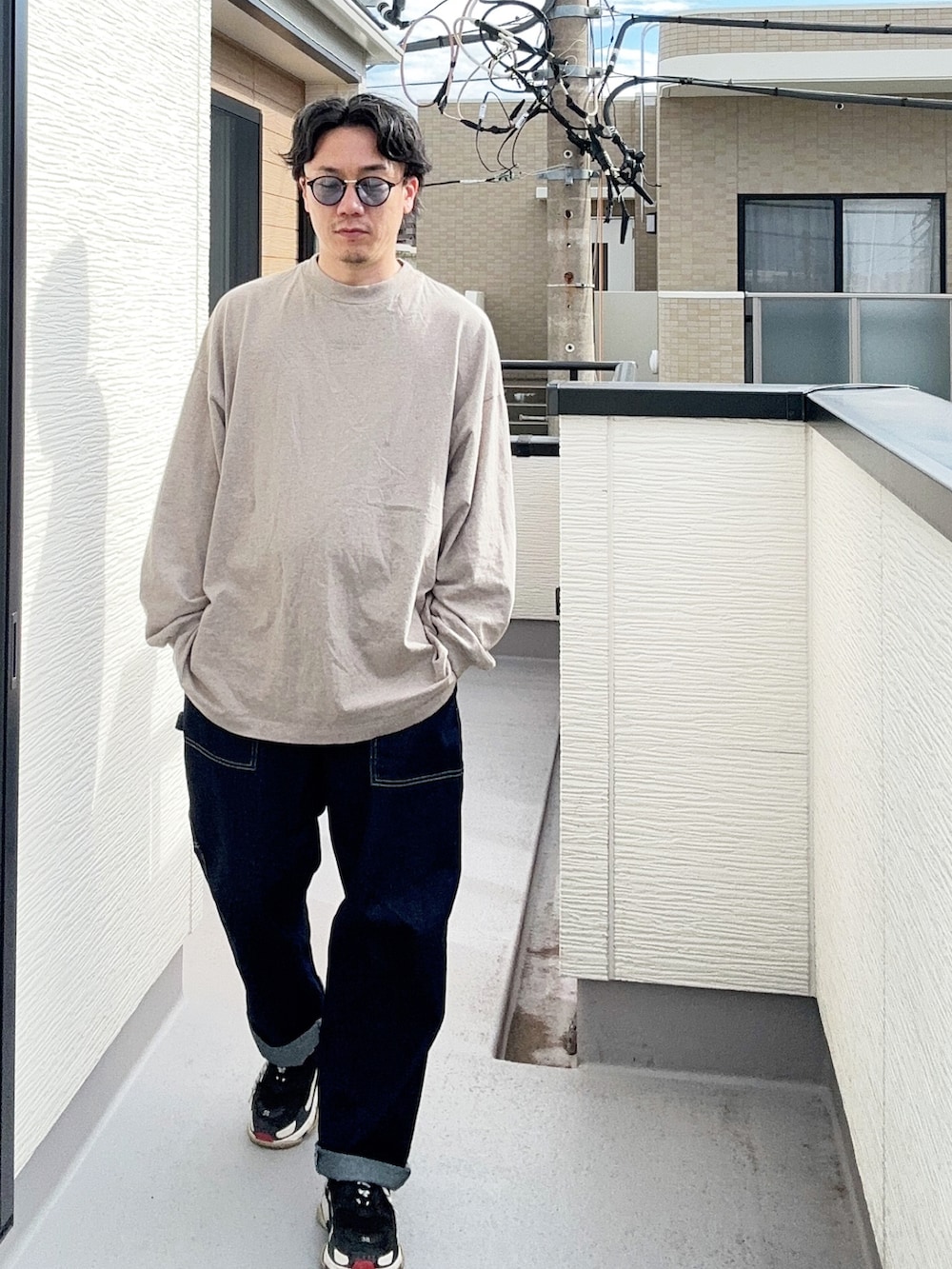 グレー系のTシャツ/カットソー、ブルー系のデニムパンツ、ブラック系のスニーカーを着用したメンズの秋コーディネートの3枚目の写真