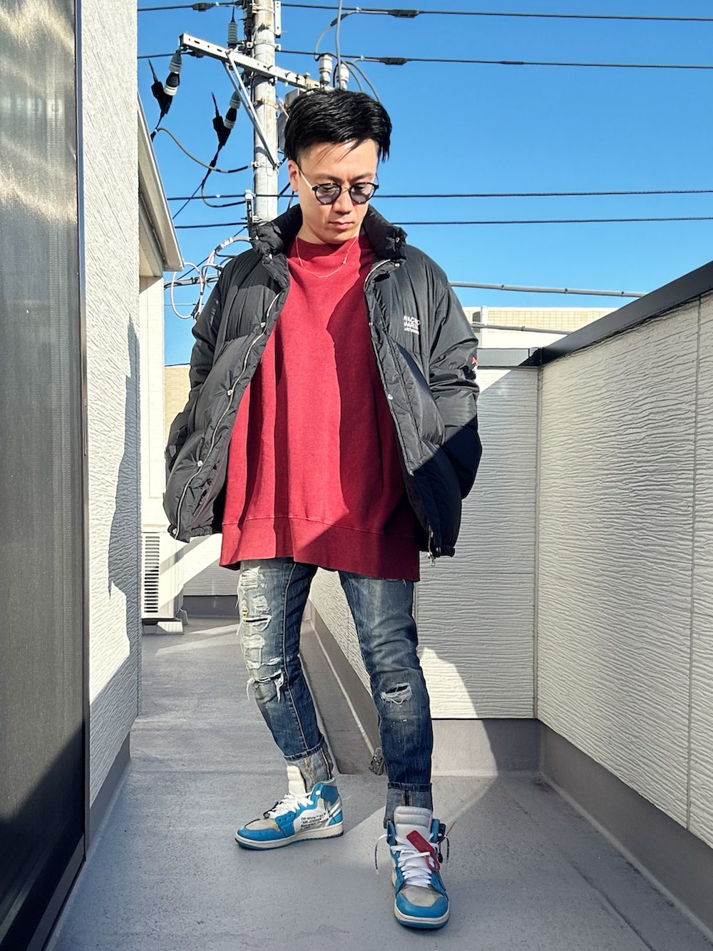 レッド系のスウェット、ブラック系のその他アウター、ブルー系のデニムパンツを着用したメンズの冬コーディネートの3枚目の写真