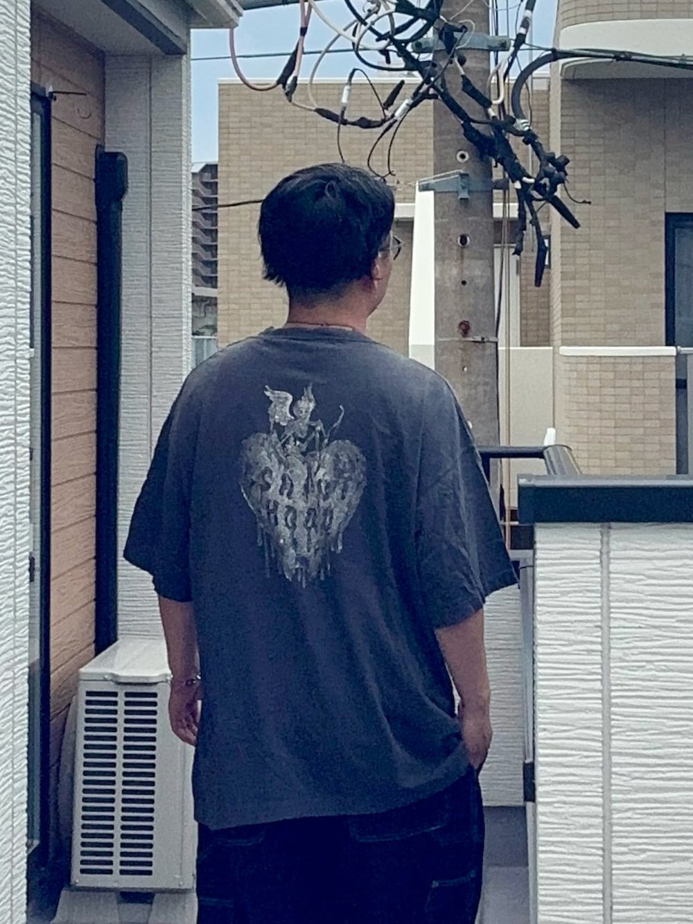 ブルー系のデニムパンツ、ブラック系のTシャツ/カットソー、ブラウン系のローファーを着用したメンズの夏コーディネートの4枚目の写真
