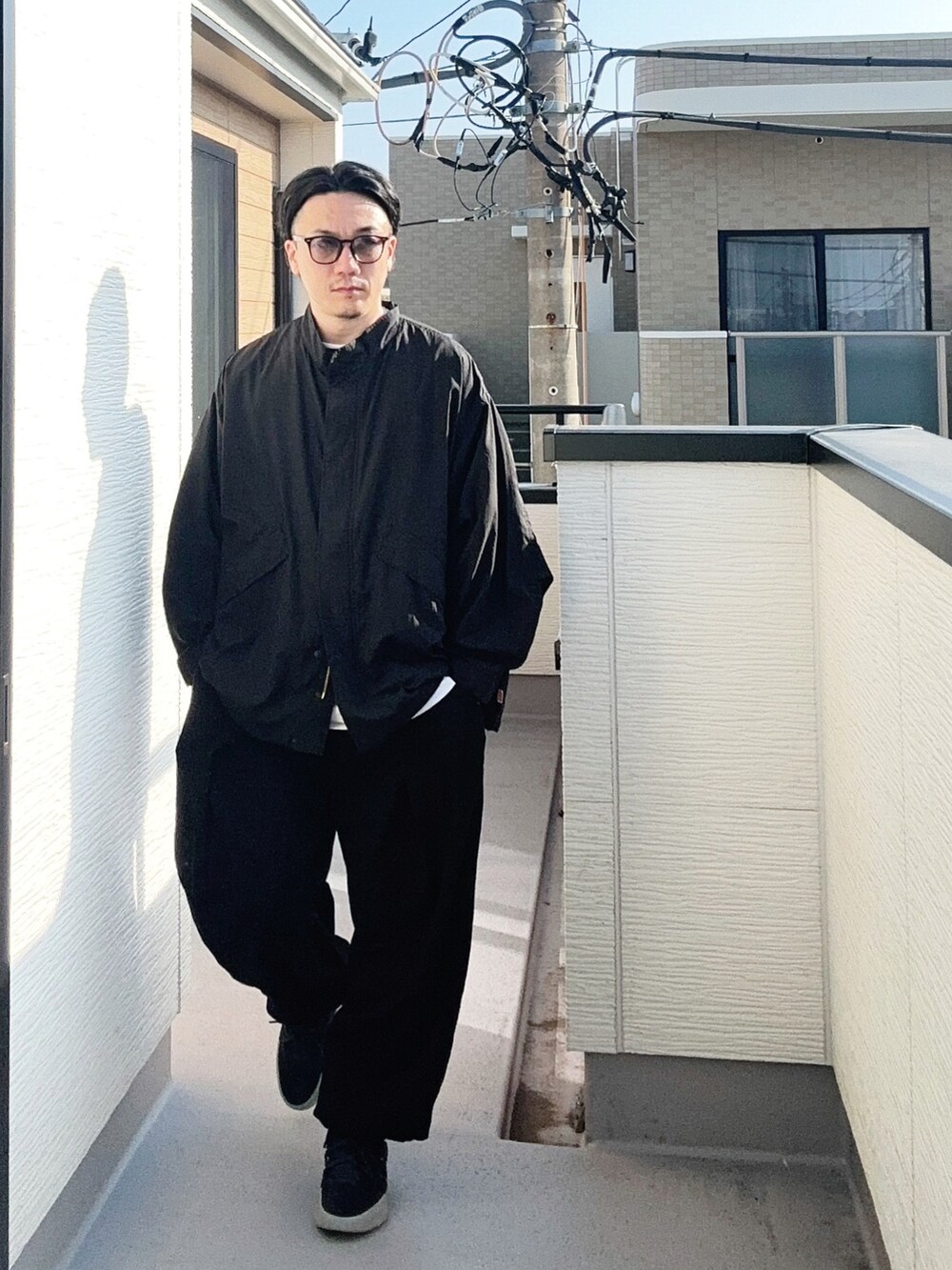 ブラック系のブルゾン、ホワイト系のTシャツ/カットソー、ブラック系のスウェットパンツを着用したメンズの秋コーディネートの2枚目の写真