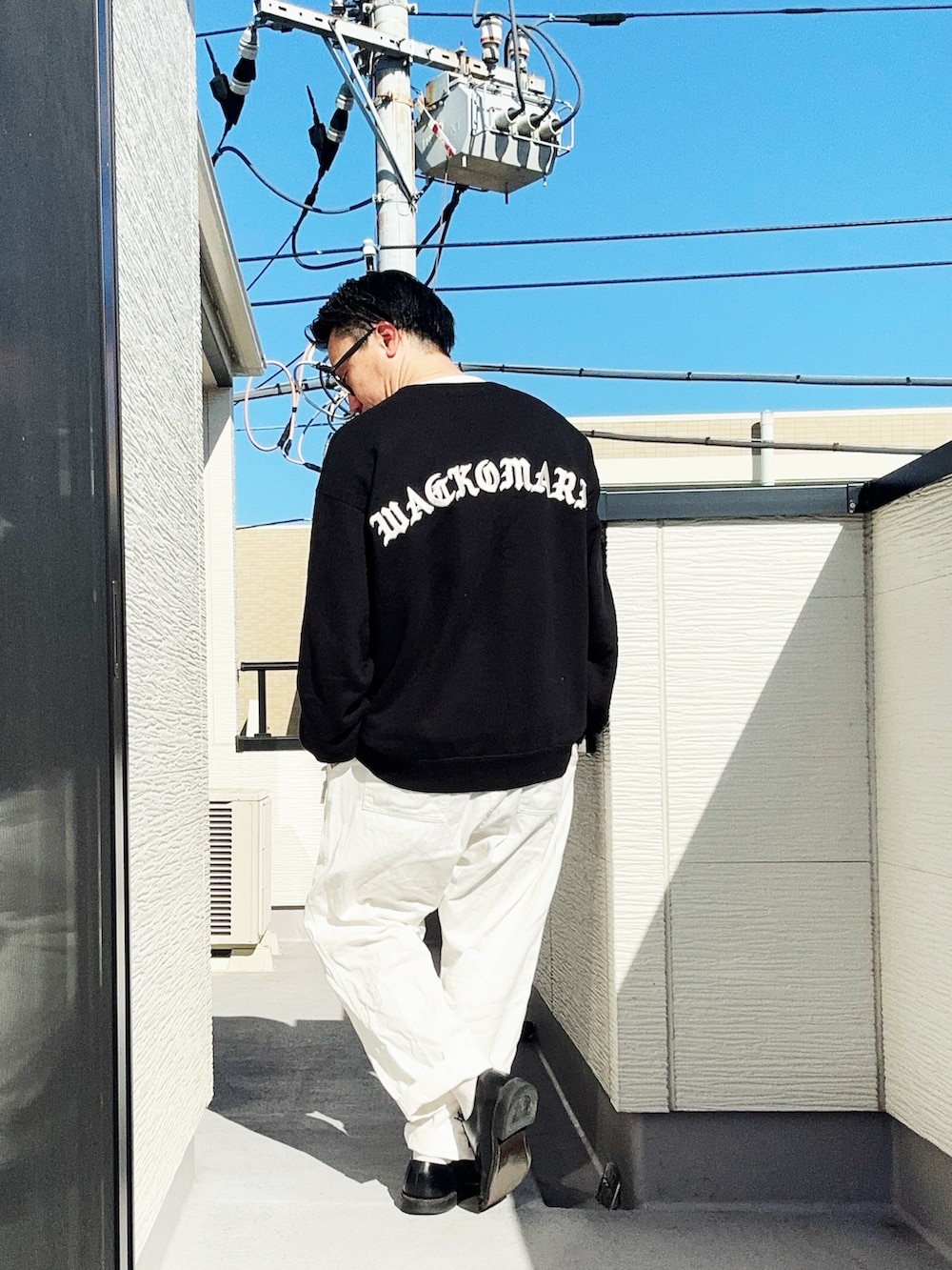 ホワイト系のデニムパンツ、ブラック系のスウェット、ブラック系のドレスシューズを着用したメンズの春コーディネートの3枚目の写真