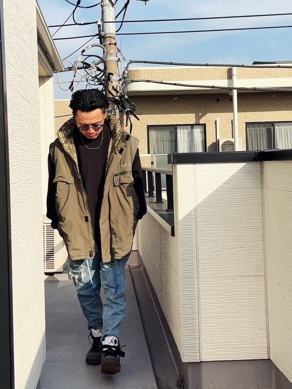 ブラック系のスウェット、ブルー系のデニムパンツ、グリーン系のミリタリージャケットを着用したメンズの冬コーディネートの2枚目の写真