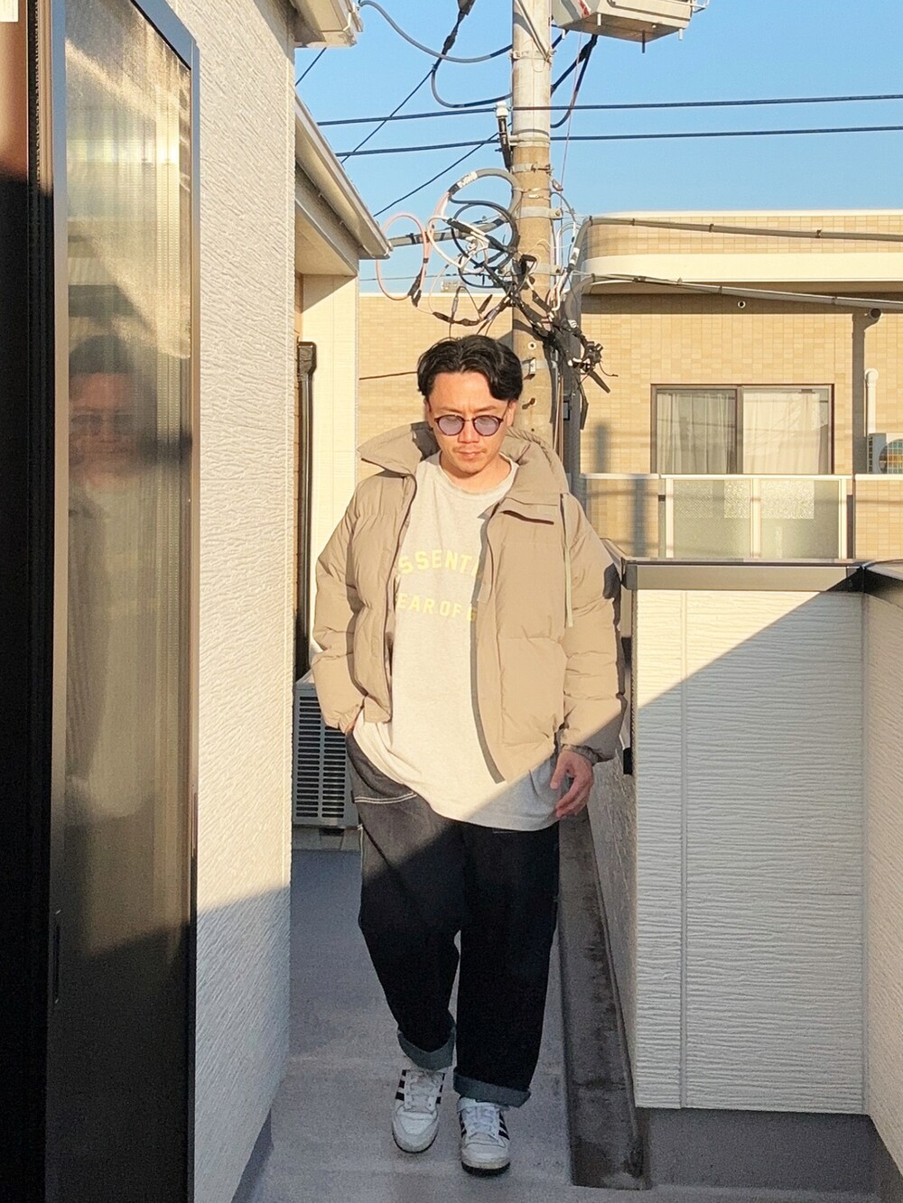 グレー系のTシャツ/カットソー、グレー系のダウンジャケット/コート、ブルー系のデニムパンツを着用したメンズの秋コーディネートの2枚目の写真