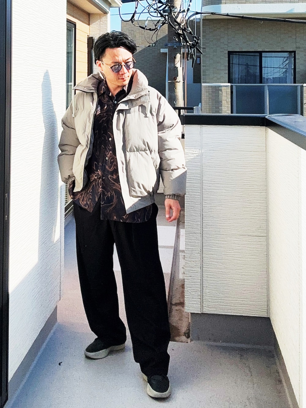 ブルー系のシャツ/ブラウス、グレー系のダウンジャケット/コート、ブラック系のスラックスを着用したメンズの冬コーディネートの4枚目の写真