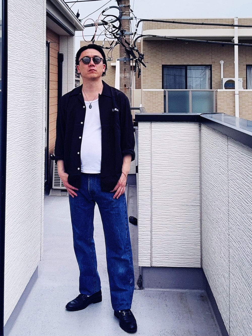 ブルー系のデニムパンツ、ブラック系のローファー、ホワイト系のタンクトップを着用したメンズの春コーディネートの3枚目の写真