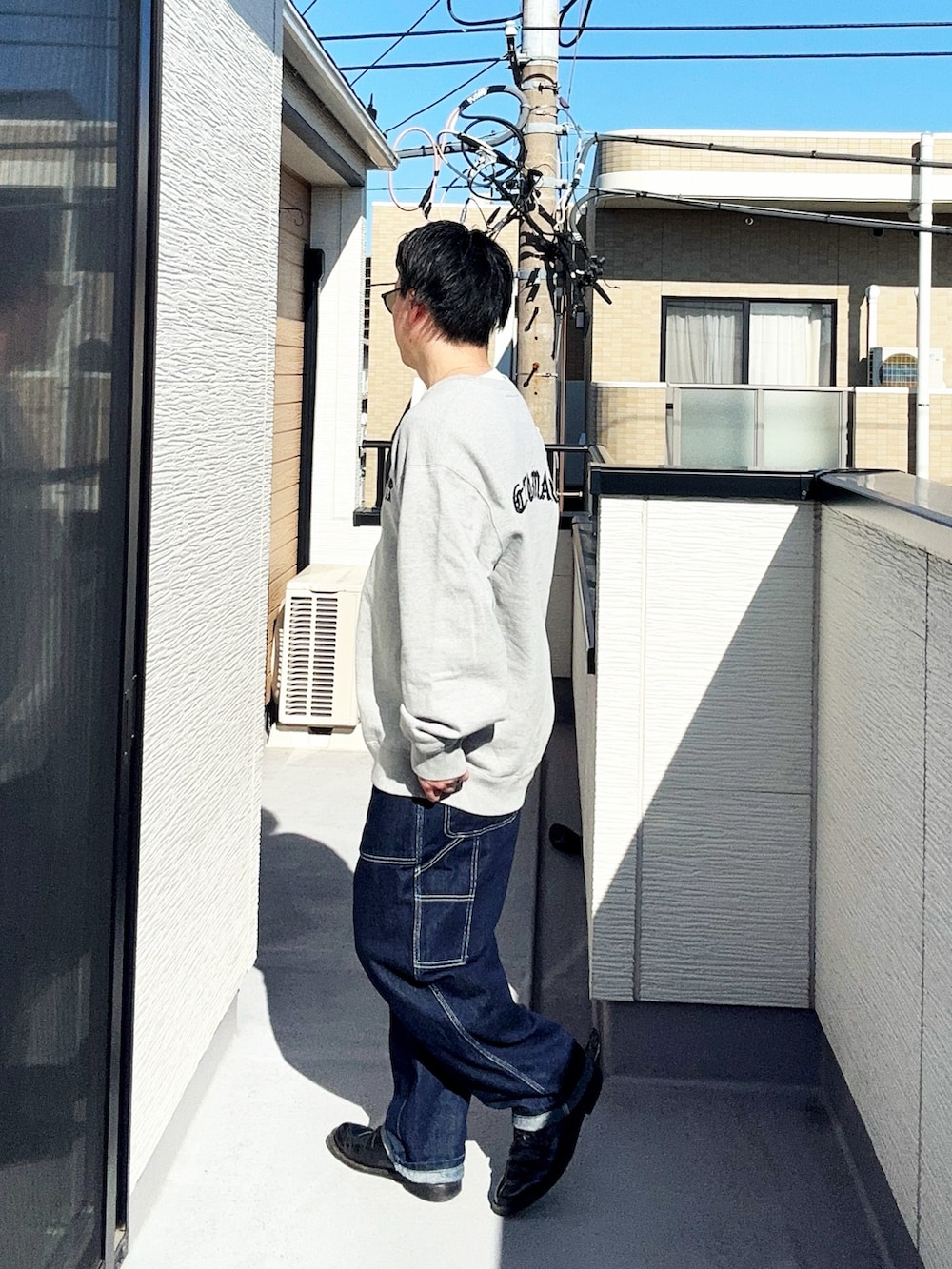 ブルー系のデニムパンツ、グレー系のスウェット、ブラック系のドレスシューズを着用したメンズの春コーディネートの2枚目の写真