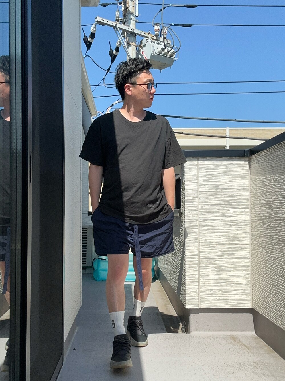 ブルー系のパンツ、ブラック系のTシャツ/カットソー、ブラック系のスニーカーを着用したメンズの夏コーディネートの3枚目の写真