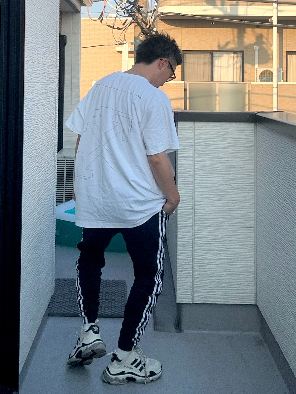 ブラック系のスウェットパンツ、ホワイト系のトップス、ホワイト系のシューズを着用したメンズの秋コーディネートの3枚目の写真