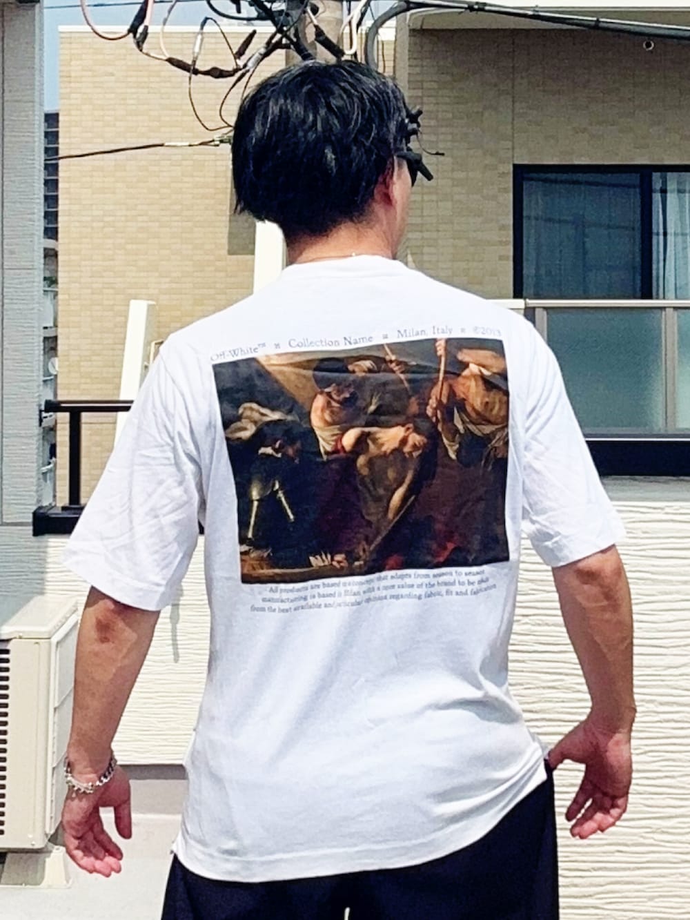 ブラック系のスラックス、ホワイト系のTシャツ/カットソー、ブラウン系のローファーを着用したメンズの夏コーディネートの4枚目の写真