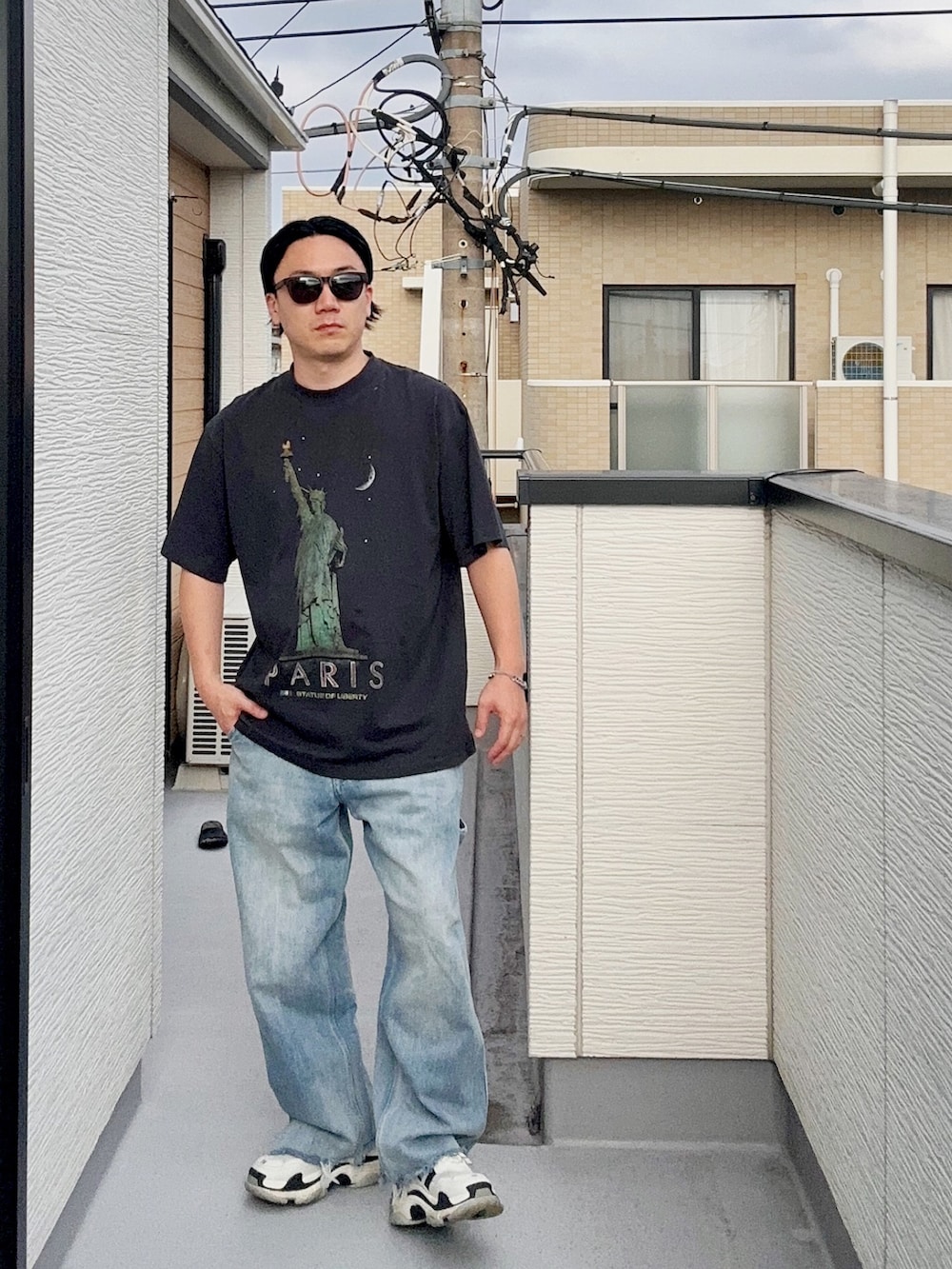 ブルー系のデニムパンツ、ブラック系のTシャツ/カットソー、ホワイト系のシューズを着用したメンズの秋コーディネートの2枚目の写真