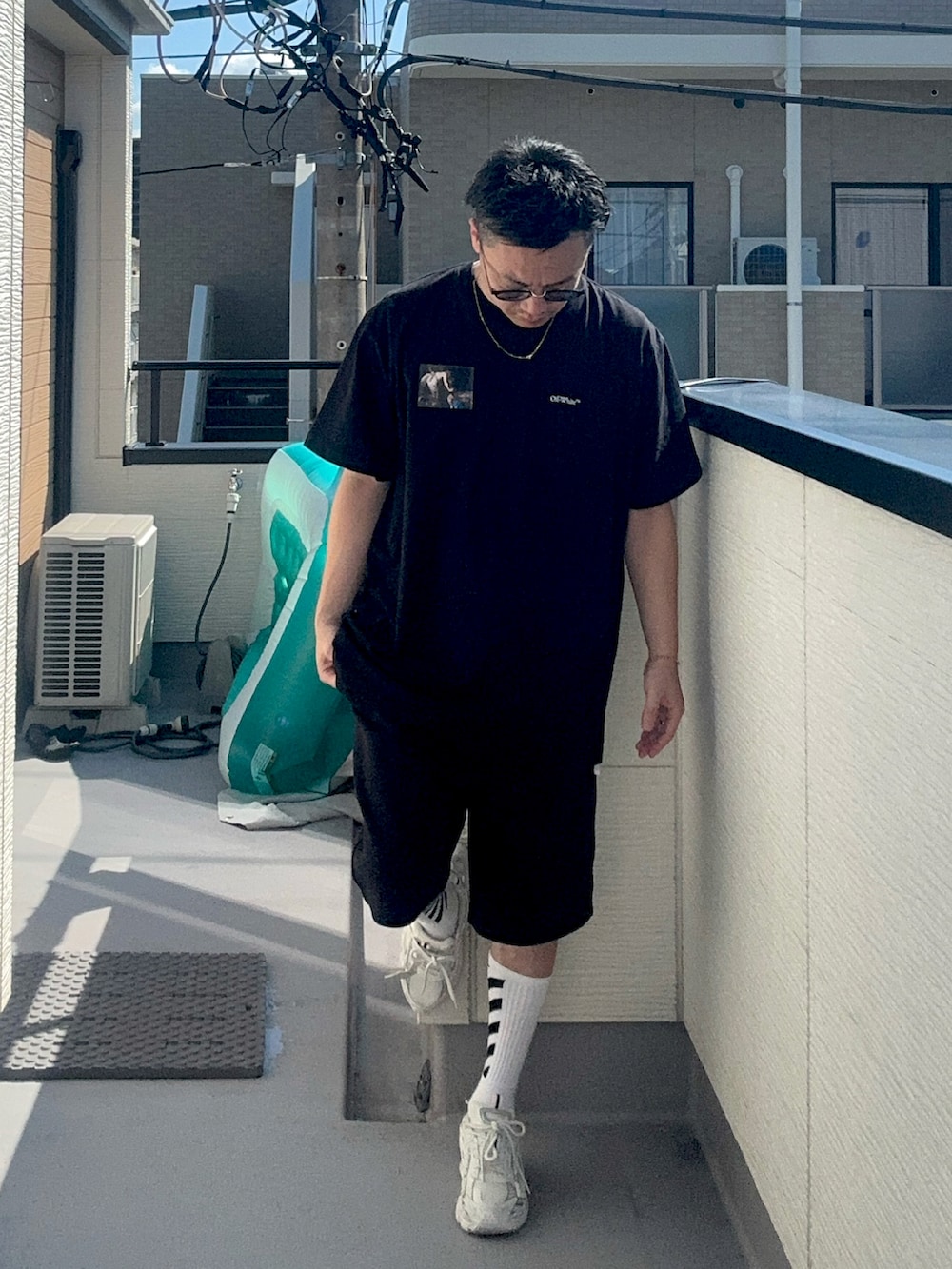 ブラック系のTシャツ/カットソー、ホワイト系のスニーカー、ホワイト系のソックス/靴下を着用したメンズの秋コーディネートの2枚目の写真