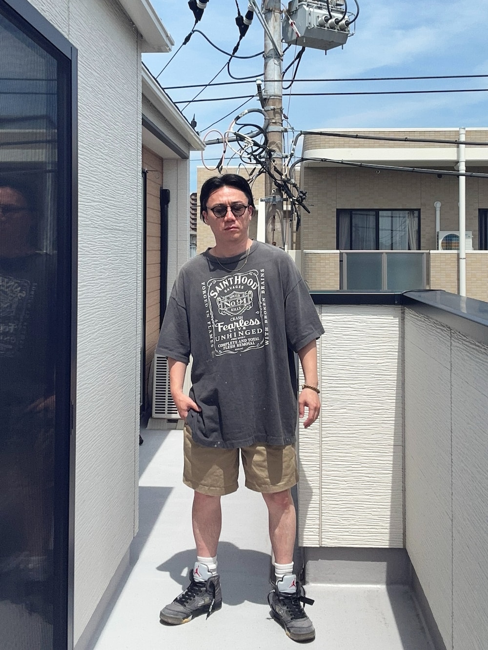 ブラック系のTシャツ/カットソー、ベージュ系のパンツ、グレー系のスニーカーを着用したメンズの夏コーディネートの2枚目の写真