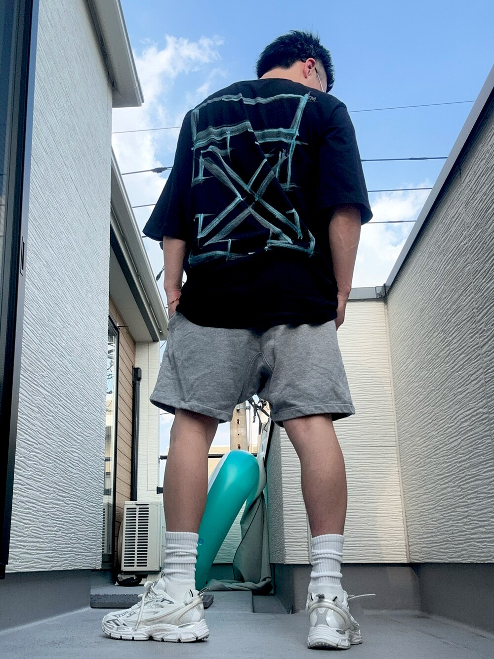 ブラック系のTシャツ/カットソー、グレー系のパンツ、ホワイト系のスニーカーを着用したメンズの夏コーディネートの4枚目の写真