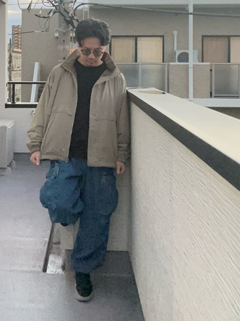 ブラック系のTシャツ/カットソー、ベージュ系のブルゾン、ブルー系のカーゴパンツを着用したメンズの秋コーディネートの2枚目の写真