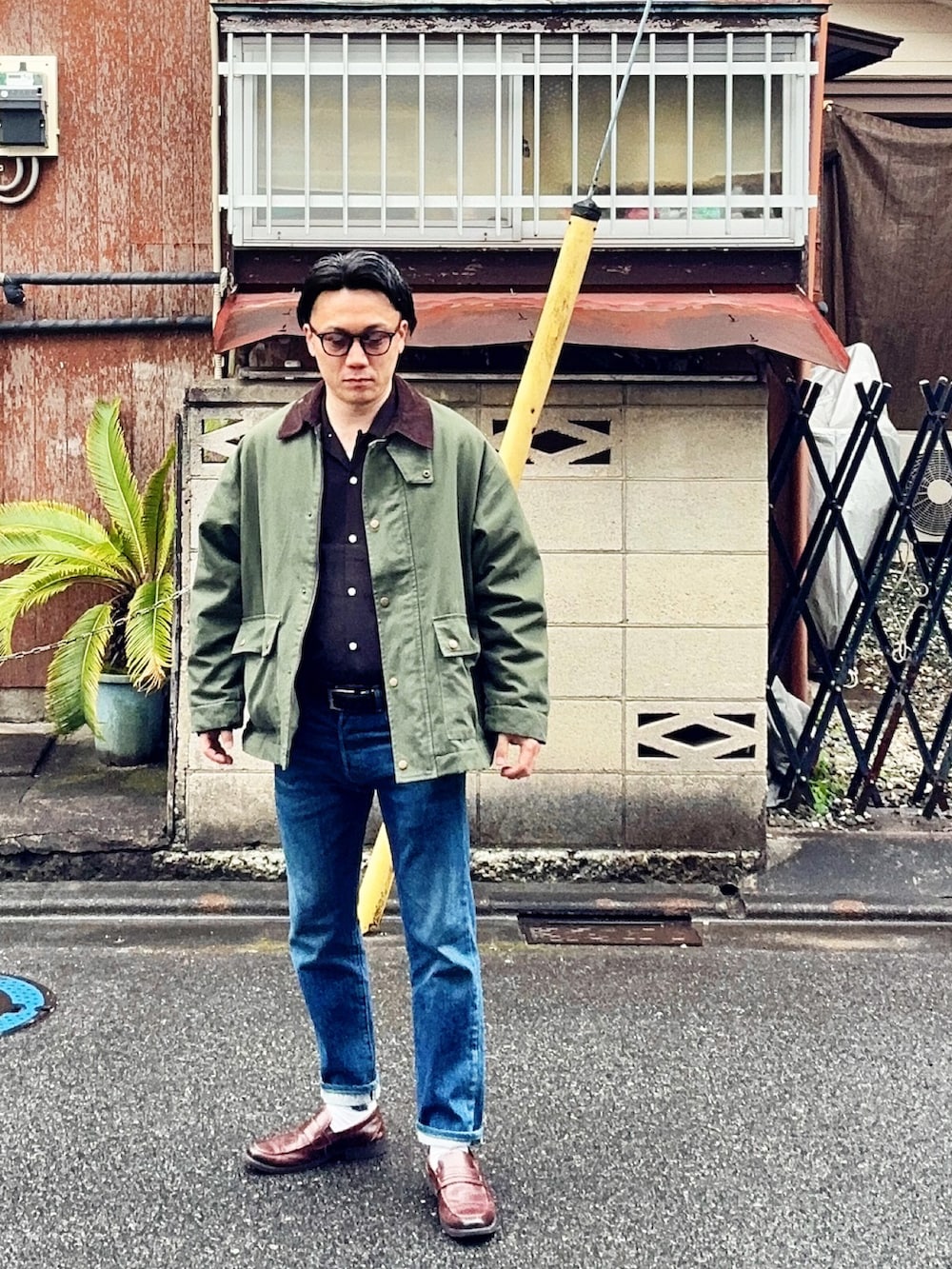 ブルー系のデニムパンツ、ブラック系のシャツ/ブラウス、グリーン系のミリタリージャケットを着用したメンズの春コーディネートの2枚目の写真