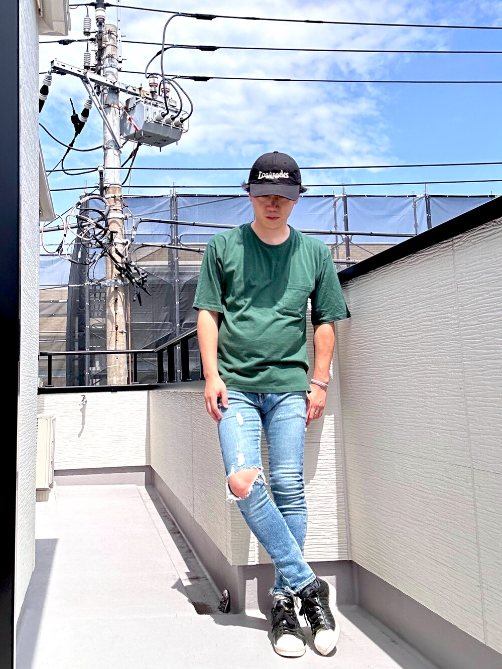 グリーン系のTシャツ/カットソー、ブルー系のデニムパンツ、ブラック系のスニーカーを着用したメンズの夏コーディネートの2枚目の写真