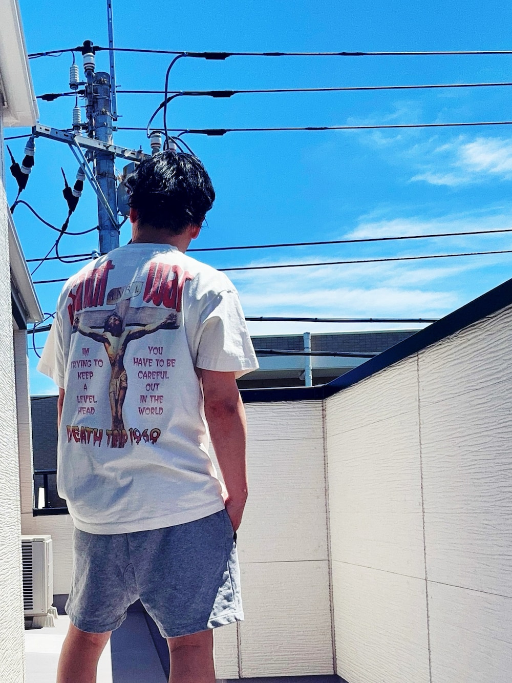 ホワイト系のTシャツ/カットソー、グレー系のパンツ、ブルー系のスニーカーを着用したメンズの春コーディネートの3枚目の写真