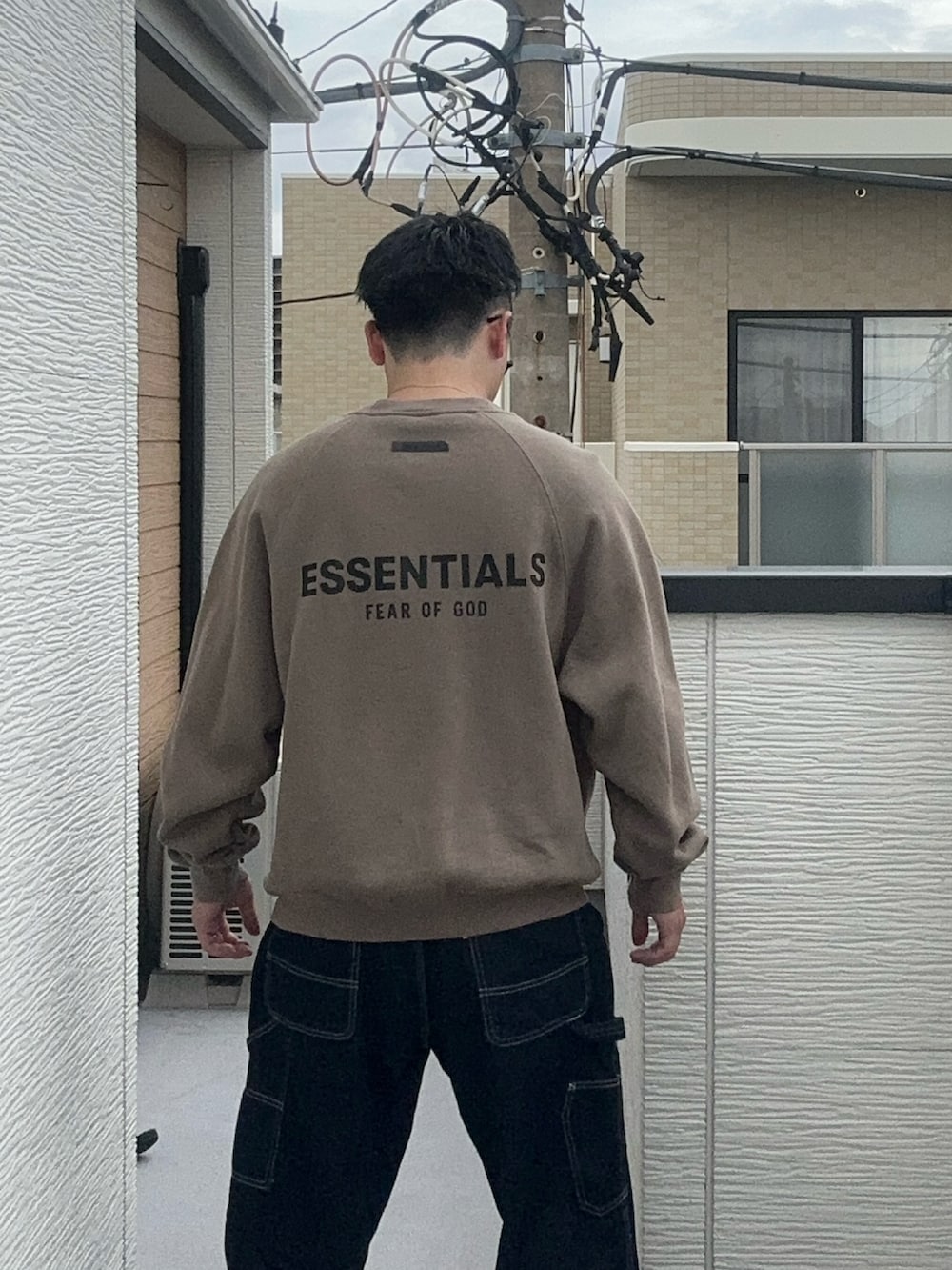 ベージュ系のスウェット、ブルー系のデニムパンツ、ブラック系のシューズを着用したメンズの秋コーディネートの4枚目の写真