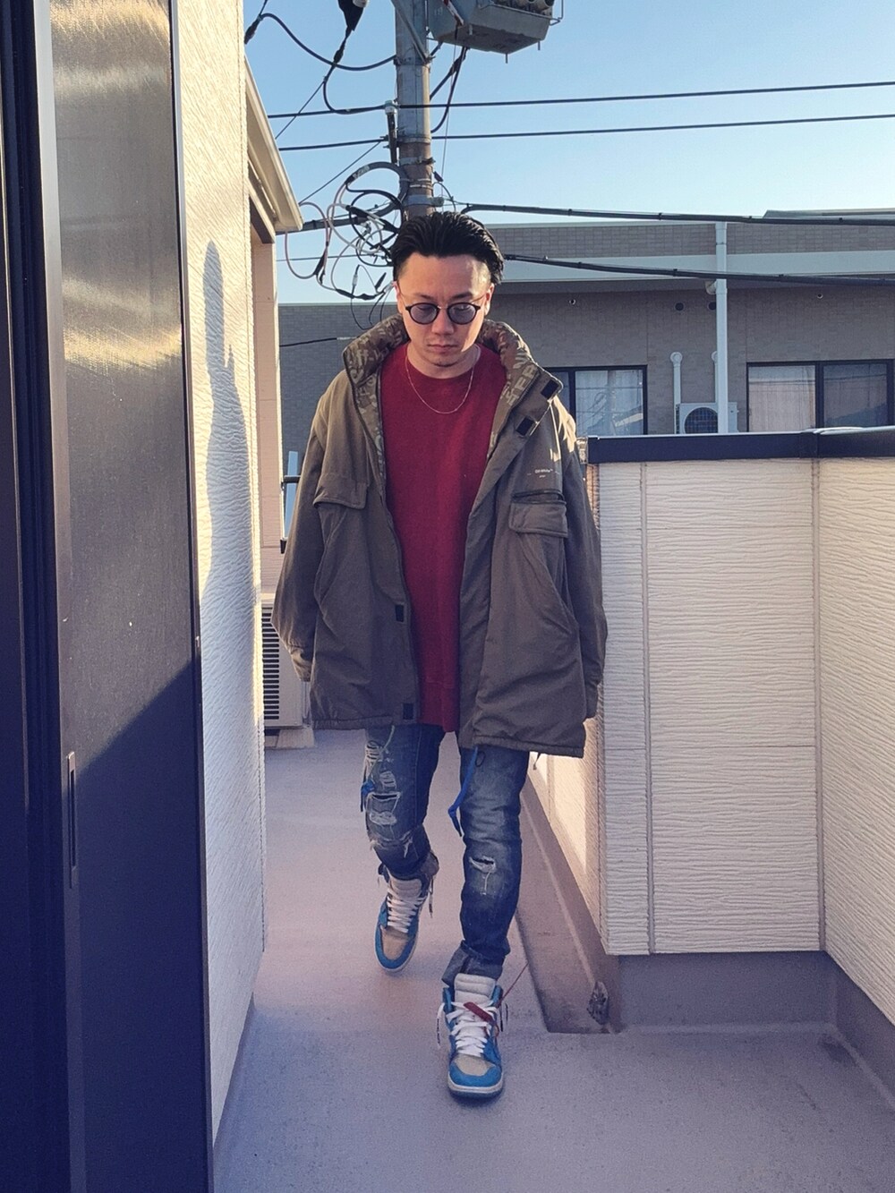 レッド系のスウェット、ブルー系のデニムパンツ、グリーン系のミリタリージャケットを着用したメンズの冬コーディネートの3枚目の写真
