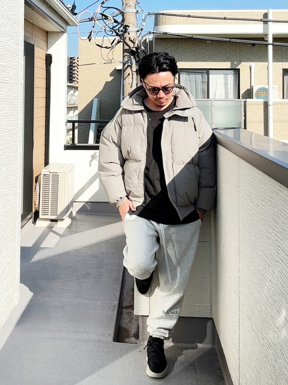 ブラック系のTシャツ/カットソー、グレー系のダウンジャケット/コート、グレー系のスウェットパンツを着用したメンズの秋コーディネートの2枚目の写真