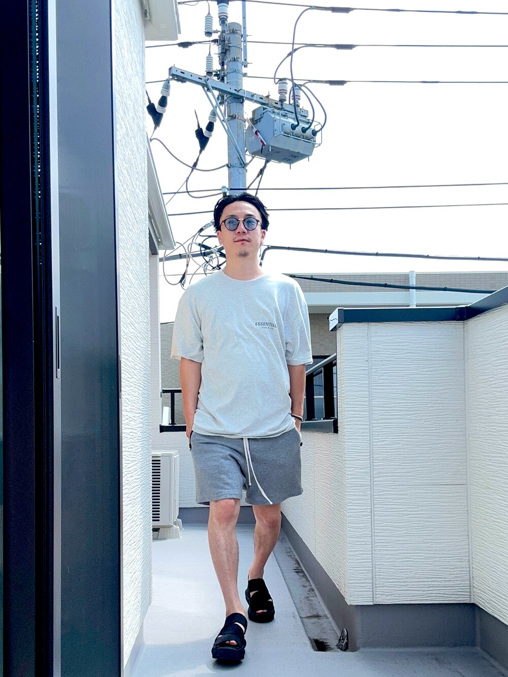 グレー系のTシャツ/カットソー、グレー系のパンツ、ブラック系のサンダルを着用したメンズの夏コーディネートの2枚目の写真