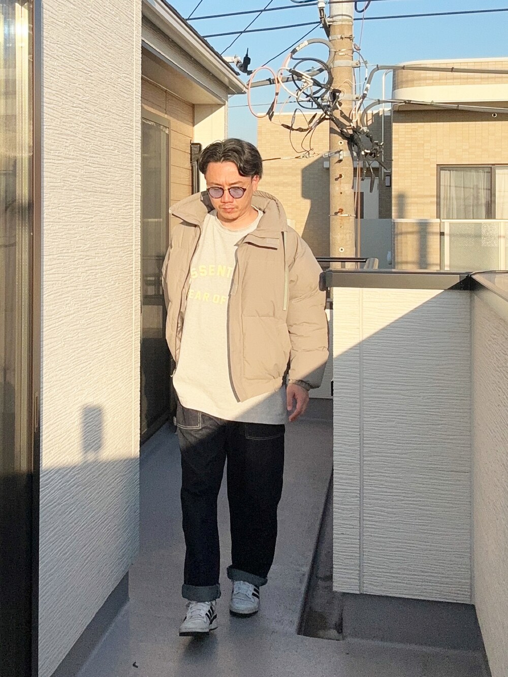 グレー系のTシャツ/カットソー、グレー系のダウンジャケット/コート、ブルー系のデニムパンツを着用したメンズの秋コーディネートの3枚目の写真