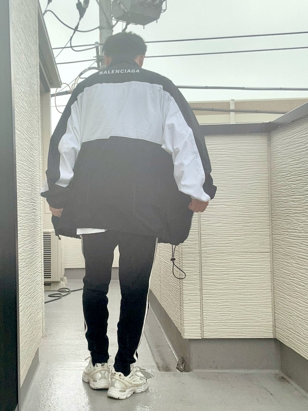 ホワイト系のトップス、ブラック系のナイロンジャケット、ブラック系のパンツを着用したメンズの秋コーディネートの3枚目の写真