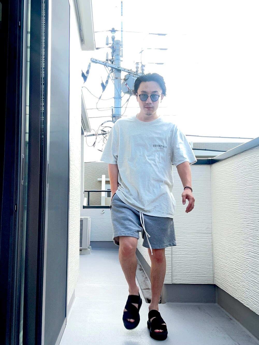 グレー系のTシャツ/カットソー、グレー系のパンツ、ブラック系のサンダルを着用したメンズの夏コーディネートの5枚目の写真
