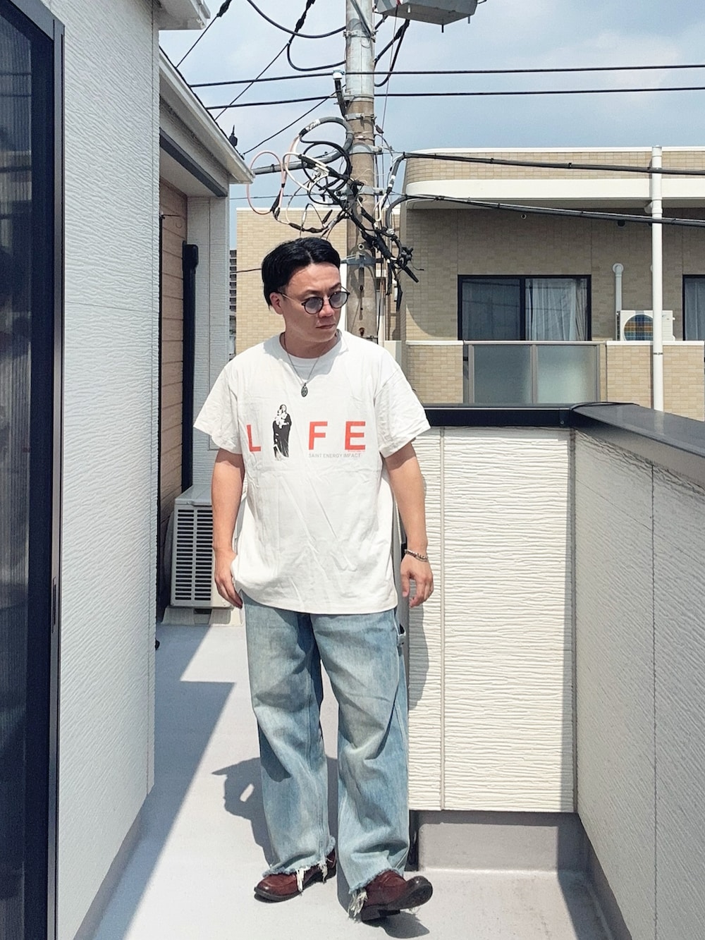 ブルー系のデニムパンツ、ホワイト系のTシャツ/カットソー、ブラウン系のローファーを着用したメンズの夏コーディネートの2枚目の写真