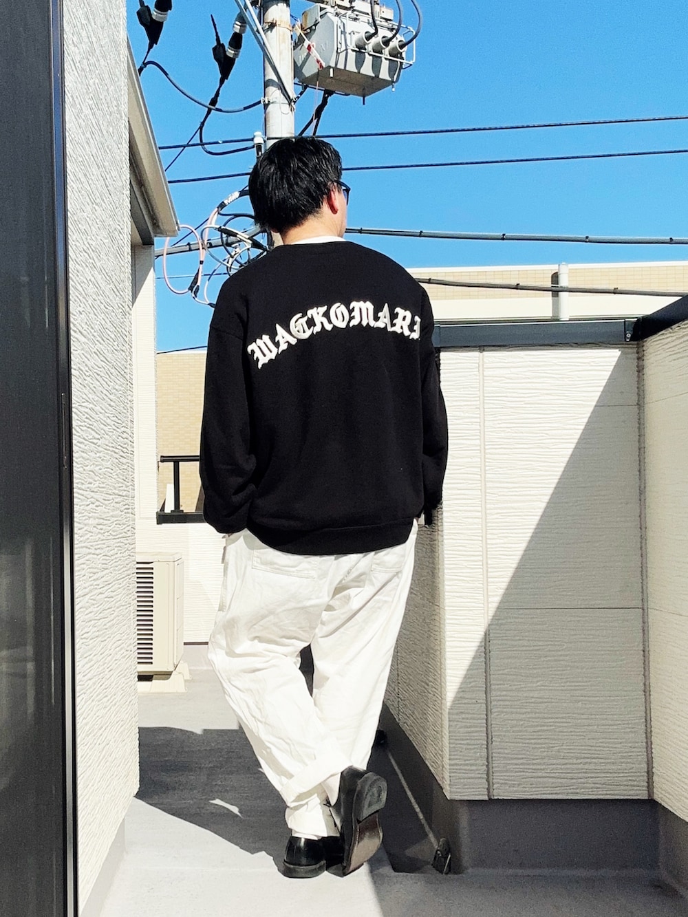 ホワイト系のデニムパンツ、ブラック系のスウェット、ブラック系のドレスシューズを着用したメンズの春コーディネートの4枚目の写真