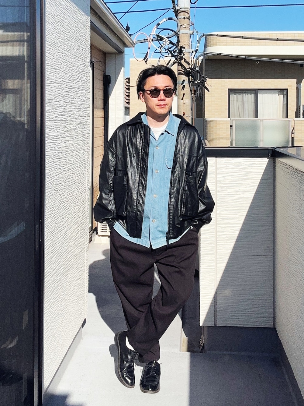 ブラック系のブルゾン、ブラック系のスラックス、ブルー系のシャツ/ブラウスを着用したメンズの春コーディネートの2枚目の写真