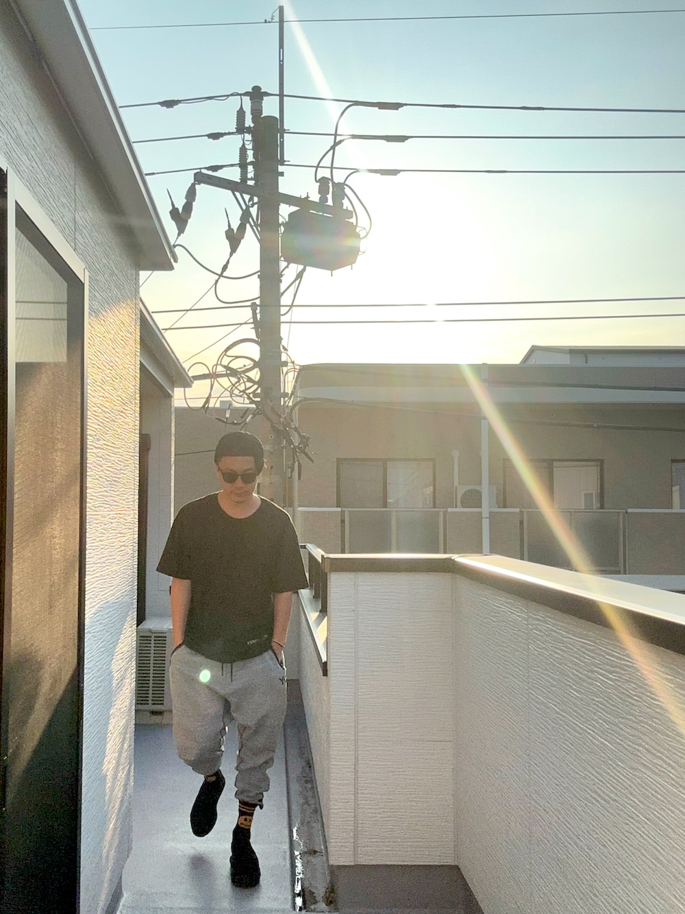 ブラック系のTシャツ/カットソー、グレー系のパンツ、ブラック系のサンダルを着用したメンズの夏コーディネートの2枚目の写真