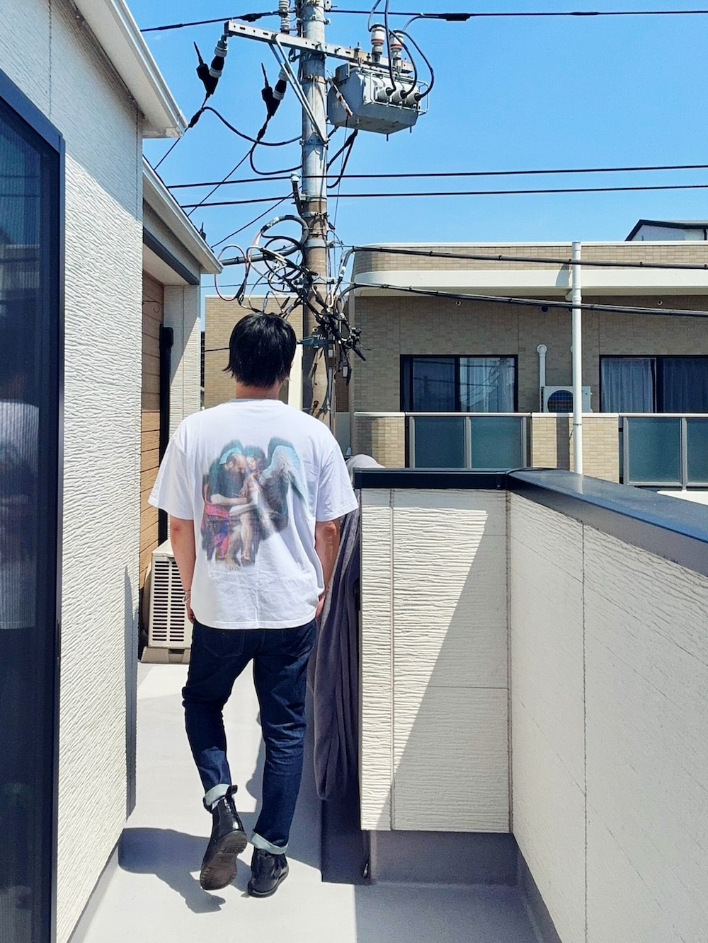 ホワイト系のTシャツ/カットソー、ブルー系のデニムパンツ、ブラック系のブーツを着用したメンズの春コーディネートの2枚目の写真