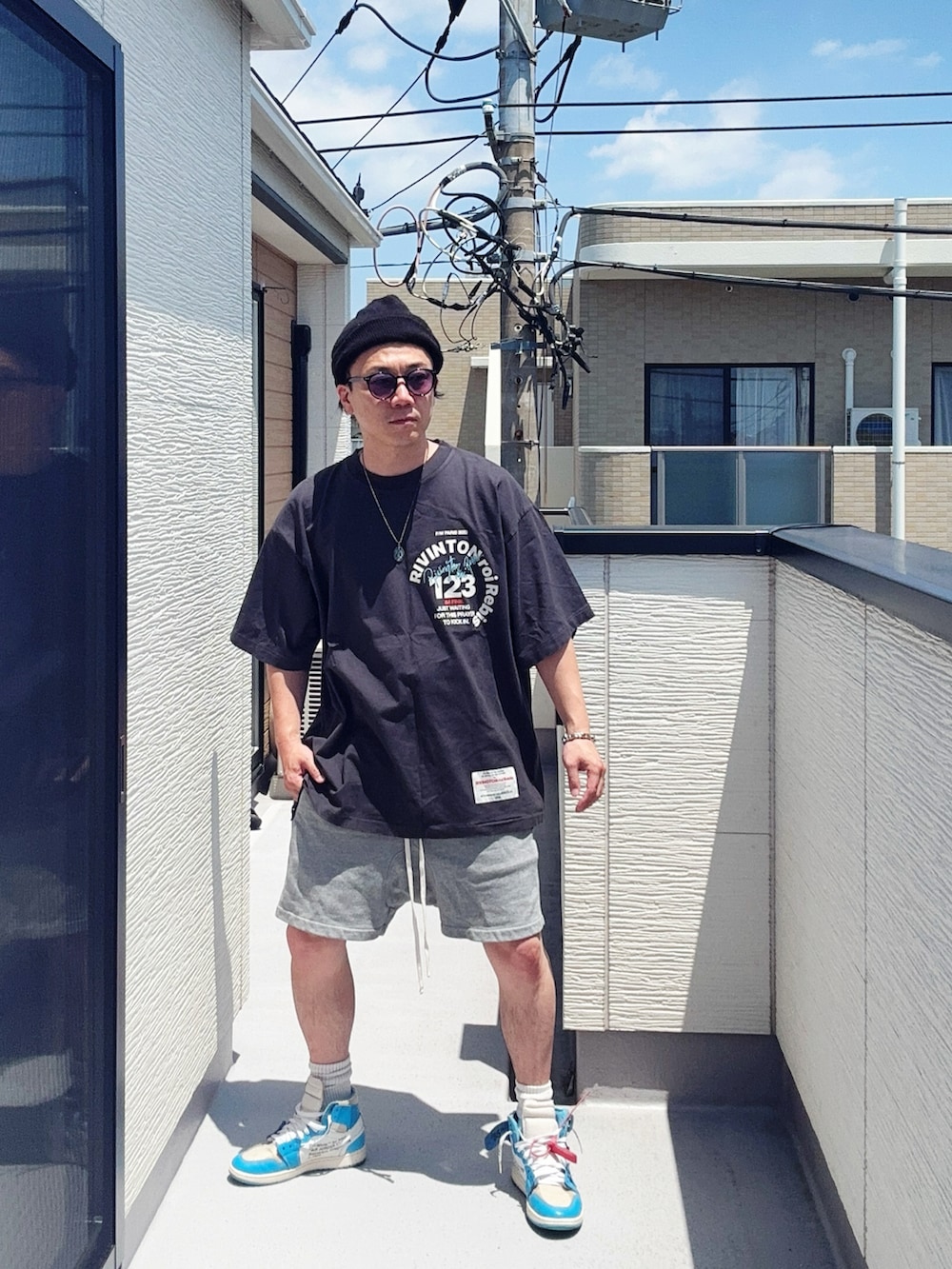 ブラック系のTシャツ/カットソー、グレー系のパンツ、ブルー系のスニーカーを着用したメンズの夏コーディネートの2枚目の写真