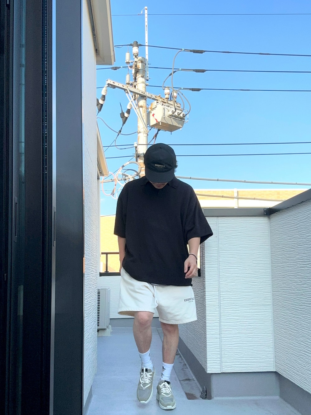 ホワイト系のスウェットパンツ、ブラック系のポロシャツ、グレー系のスニーカーを着用したメンズの夏コーディネートの4枚目の写真