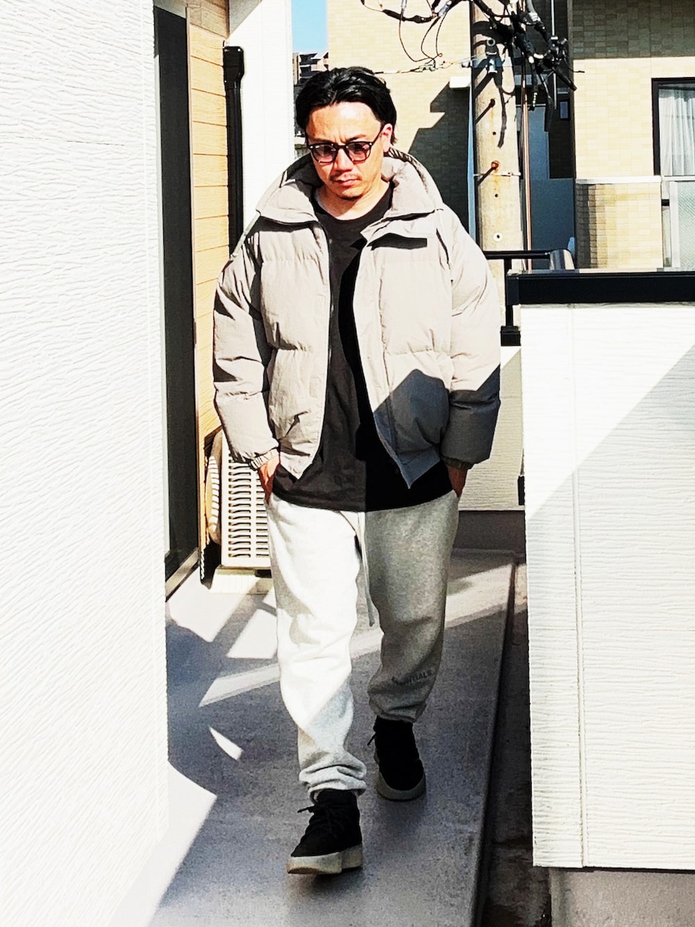 ブラック系のTシャツ/カットソー、グレー系のダウンジャケット/コート、グレー系のスウェットパンツを着用したメンズの秋コーディネートの3枚目の写真