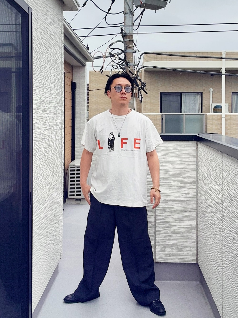 グレー系のスラックス、ブラック系のローファー、ホワイト系のTシャツ/カットソーを着用したメンズの夏コーディネートの2枚目の写真
