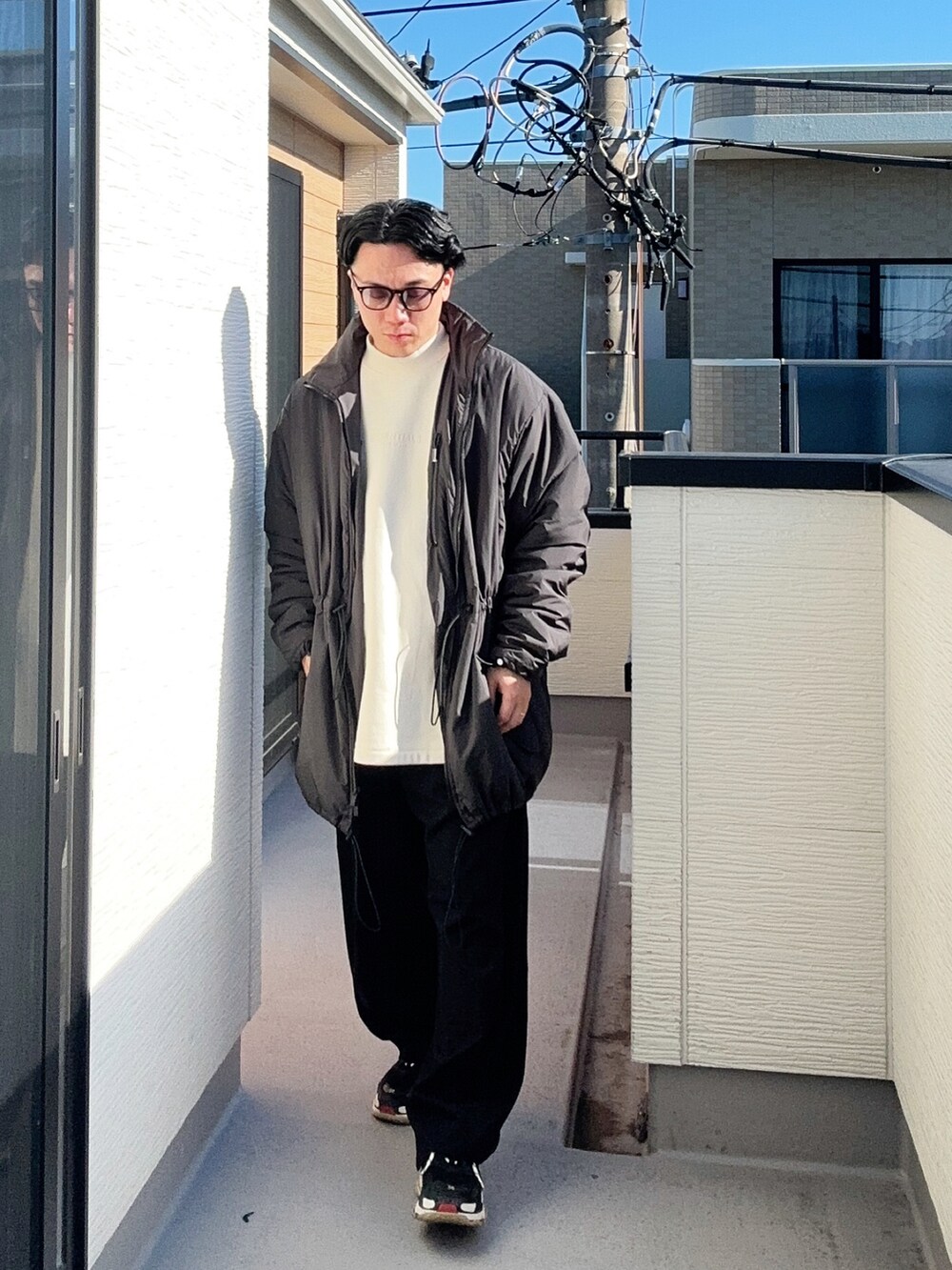 ベージュ系のスウェット、ブラック系のその他アウター、ブラック系のスラックスを着用したメンズの冬コーディネートの3枚目の写真