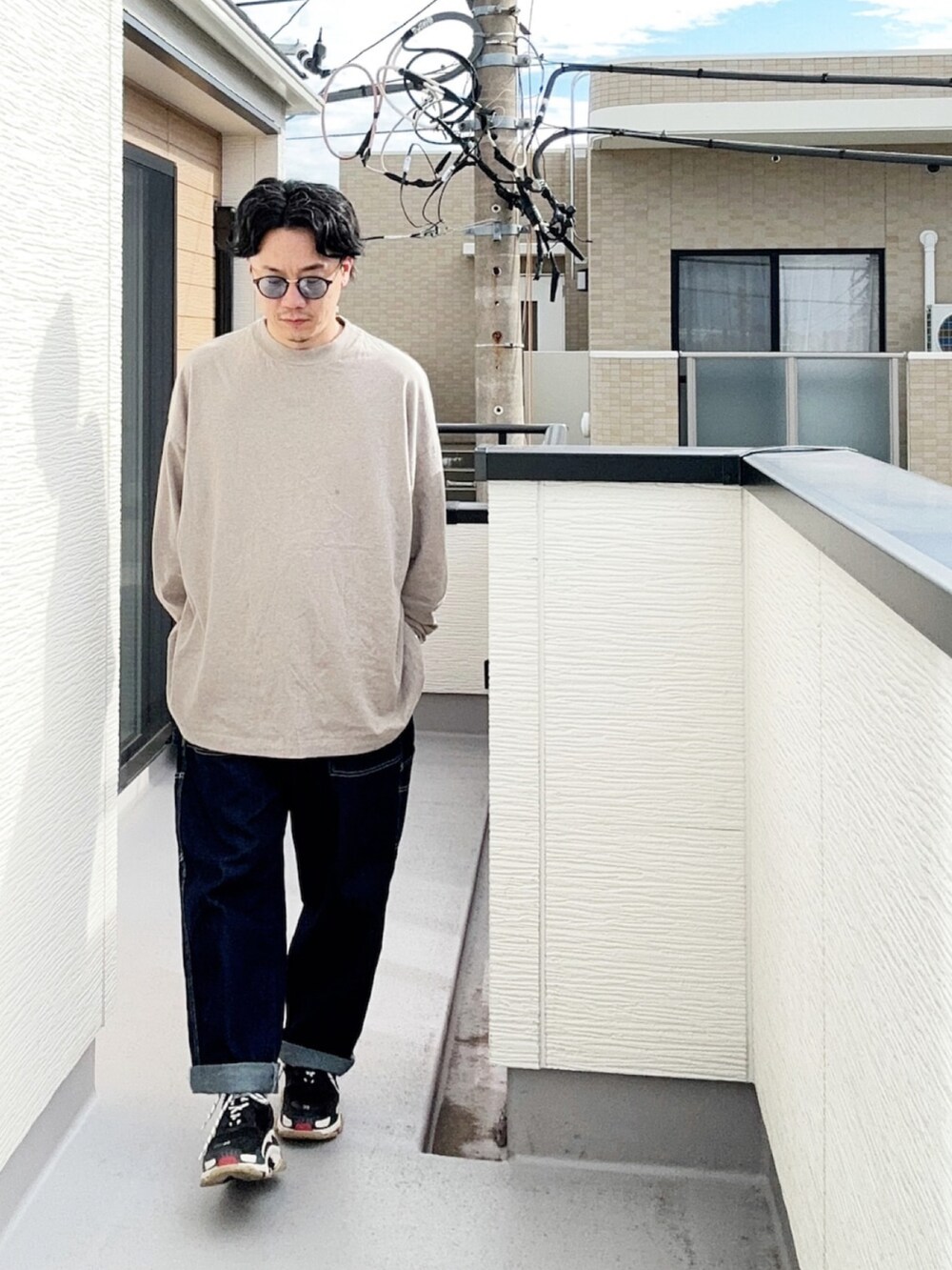 グレー系のTシャツ/カットソー、ブルー系のデニムパンツ、ブラック系のスニーカーを着用したメンズの秋コーディネートの2枚目の写真