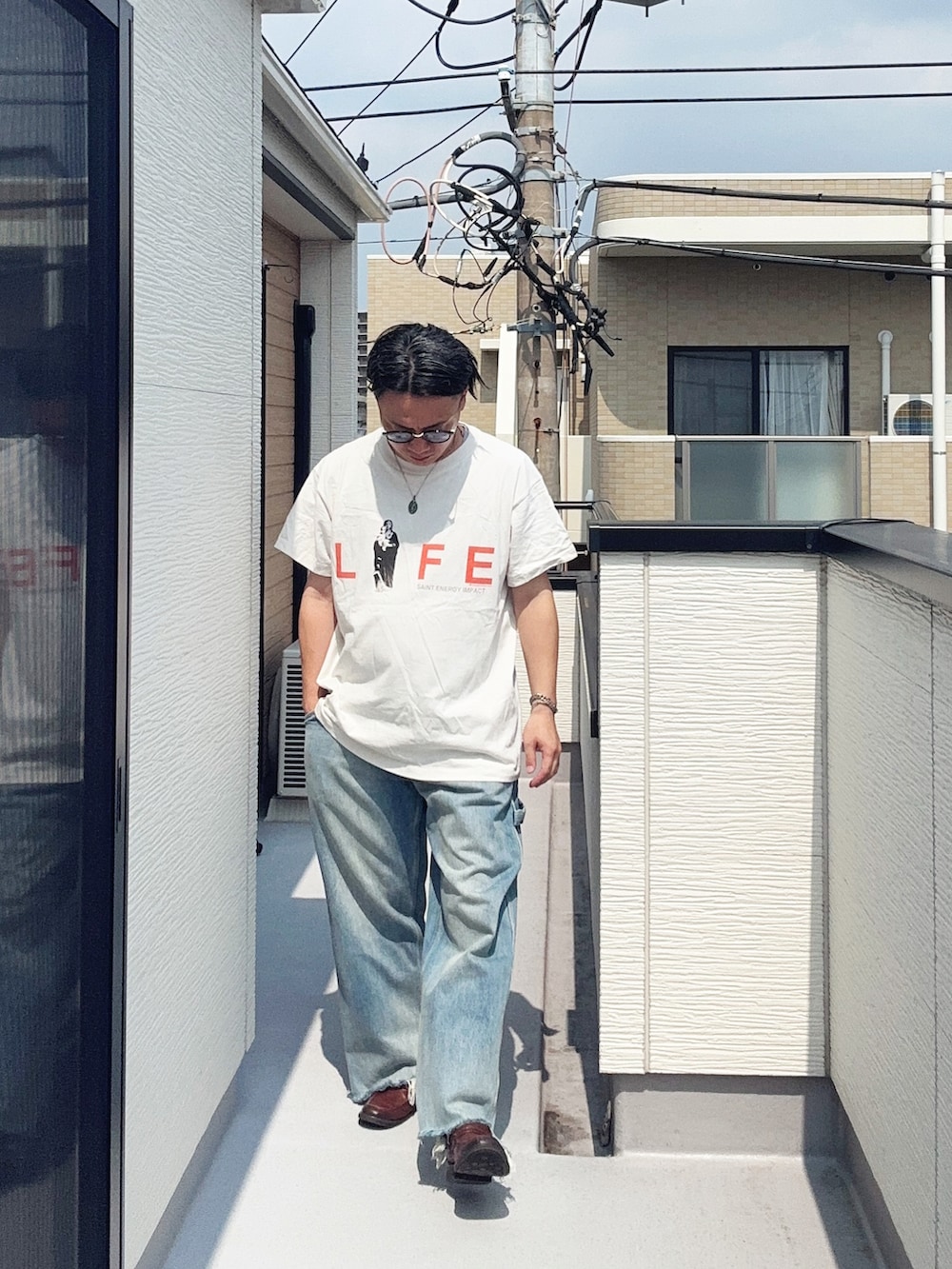 ブルー系のデニムパンツ、ホワイト系のTシャツ/カットソー、ブラウン系のローファーを着用したメンズの夏コーディネートの3枚目の写真