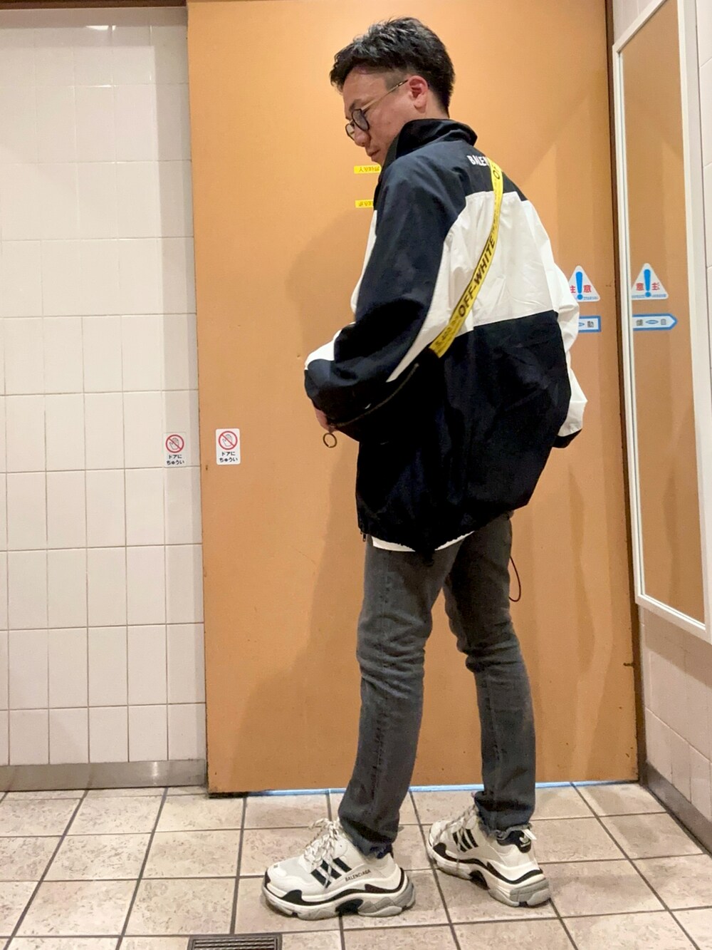 グレー系のデニムパンツ、ブラック系のショルダーバッグ、ブラック系のスニーカーを着用したメンズの秋コーディネートの3枚目の写真