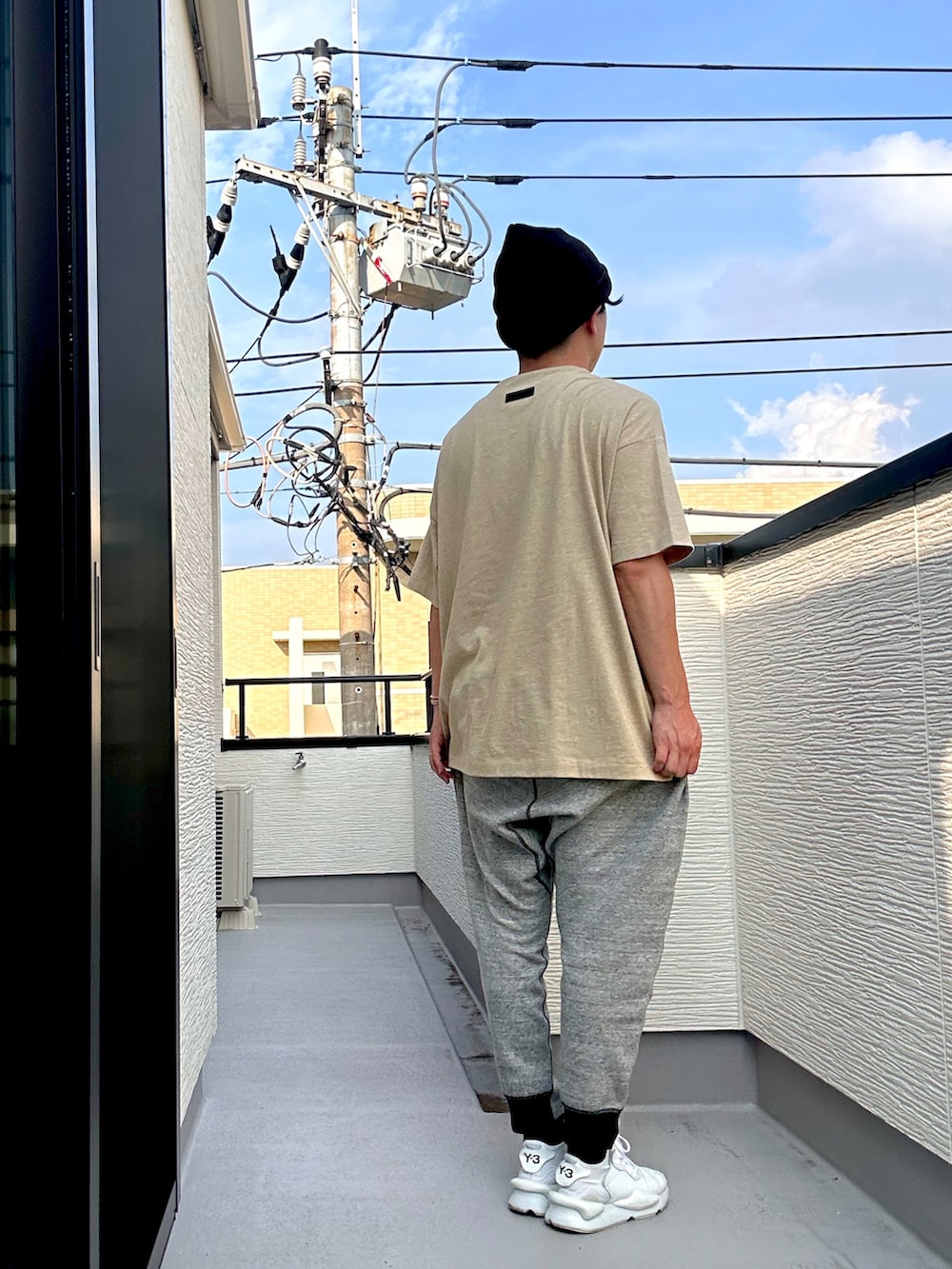 ベージュ系のTシャツ/カットソー、グレー系のパンツ、ホワイト系のスニーカーを着用したメンズの夏コーディネートの2枚目の写真