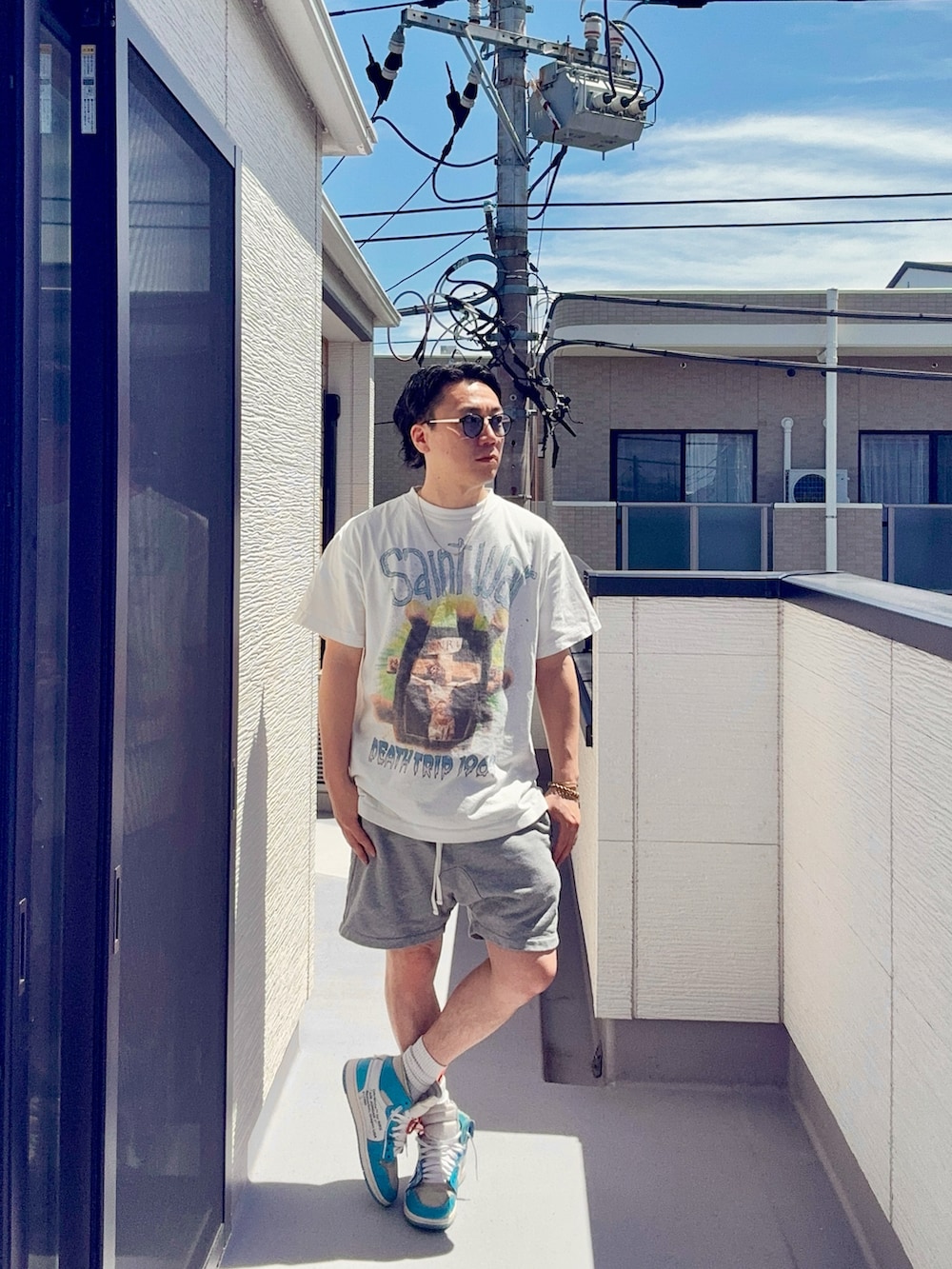 ホワイト系のTシャツ/カットソー、グレー系のパンツ、ブルー系のスニーカーを着用したメンズの春コーディネートの2枚目の写真