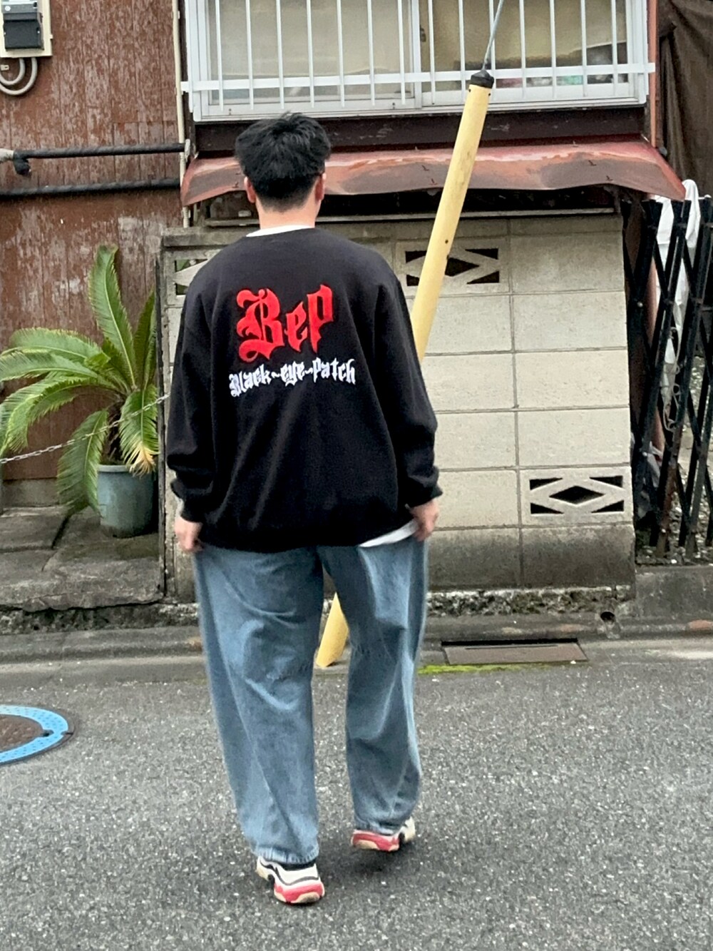 ブルー系のデニムパンツ、ブラック系のスウェット、ブラック系のスニーカーを着用したメンズの秋コーディネートの4枚目の写真